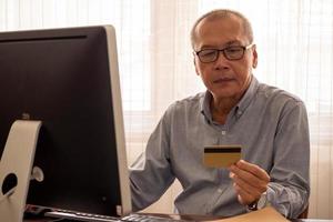 Aziatisch zakenman aan het doen financieel transacties door computer Bij de kantoor kamer. foto