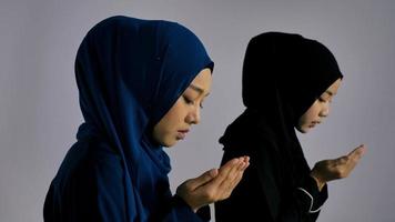 twee jonge Aziatische moslimvrouwen in traditionele hijab bidden om Allah te verheerlijken en het islamitische geloof in de moskee te beoefenen. foto
