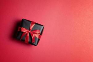 top visie van zwart geschenk doos met rood en zwart linten geïsoleerd Aan rood achtergrond. foto