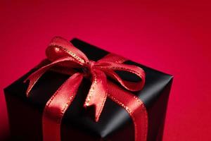 top visie van zwart geschenk doos met rood en zwart linten geïsoleerd Aan rood achtergrond. foto