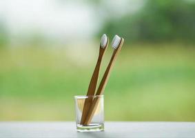 nul verspilling badkamer gebruik minder plastic concept bamboe tandenborstel in glas Aan natuur groen achtergrond foto