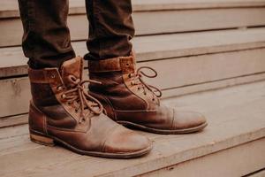 afbeelding van mans bruin schoeisel staande op houten trappen. man in broek en ruige schoenen op de drempel. horizontale weergave foto