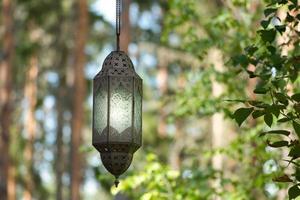 hangende lamp Aan een bijhouden in voorkant van een Woud van metaal en glas. verlicht. foto