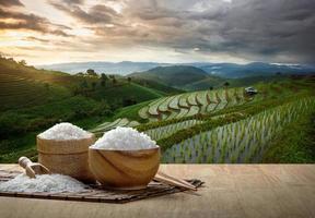Japan rijst- en gekookt rijst- in houten kom met de eetstokjes Aan de houten tafel met de plantage rijst- foto