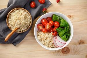 quinoa salade met groenten, framboos en tomaten Aan de houten tafel. super voedsel voor gezond en concept van evenwichtig eetpatroon foto