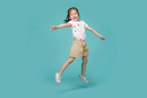 speels energiek Aziatisch weinig meisje jumping in in de lucht, leeg ruimte in studio schot geïsoleerd Aan kleurrijk blauw achtergrond foto