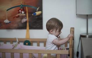 schattig weinig een jaar oud baby en maken eerste stappen in bed foto