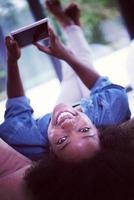Afrikaanse Amerikaans vrouw Bij huis met digitaal tablet foto
