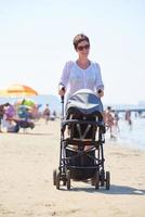 moeder wandelen Aan strand en Duwen baby vervoer foto