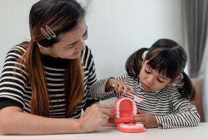 schattig aziatisch kind speelt met dokter tandarts speelgoed set, kind laat zien hoe je tanden schoonmaakt en verzorgt. tandheelkunde en geneeskunde, foto