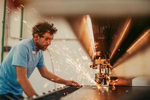 binnen zwaar industrie. een Mens werken in een modern fabriek Aan een cnc machine. selectief focus foto