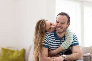 jong knap paar knuffelen Aan de sofa foto