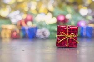 dichtbij omhoog van handgemaakt geschenk doos met rood lint Aan houten tafel voor Kerstmis of nieuw jaar decoratie achtergrond foto