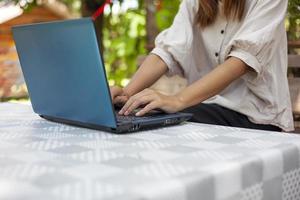 handen van een vrouw drukken een notitieboekje computer toetsenbord naar Doen sommige werk of zoeken voor informatie. foto