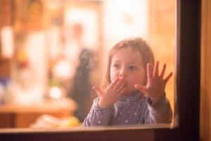 weinig schattig meisje spelen in de buurt de venster foto