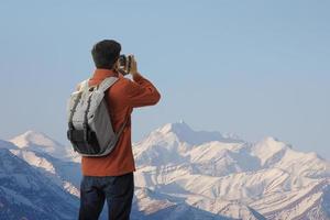 hipster jong Aziatisch Mens Aan de top van ijsberg berg met rugzak in de natuur en nemen een foto met digitaal camera de schoonheid van landschap, avontuur en reizen in de bergen regio concept