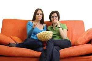 vrouw vrienden aan het eten popcorn en aan het kijken TV Bij huis foto