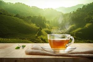 warm kop van thee en thee blad en zak Aan de houten tafel en de thee plantages achtergrond foto