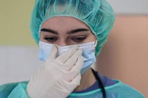 de vrouw dier chirurg of dierenarts zet Aan een medisch gezicht masker. dokter is voorbereidingen treffen voor chirurgie in de operatie kamer. geneeskunde en gezondheidszorg foto