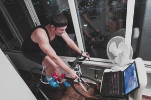 Mens wielersport Aan de machine trainer hij is oefenen in de huis Bij nacht spelen online fiets racing spel foto