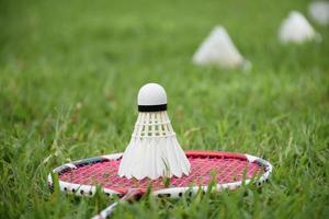 badminton racket en badminton shuttle tegen bewolkt en blauwe lucht achtergrond, buitenshuis badminton spelen concept. selectief focus Aan racket. foto