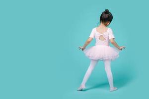 mooi glimlachen Aziatisch weinig meisje in een roze pak is dansen een ballet Bij school, leeg ruimte in studio schot geïsoleerd Aan kleurrijk blauw achtergrond foto