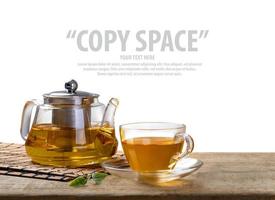 warm kop van thee en glas potten met biologisch groen thee blad Aan houten tafel isoleren wit achtergrond met kopiëren ruimte foto