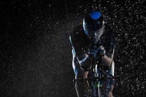 triatlon atleet rijden fiets snel Aan regenachtig nacht foto