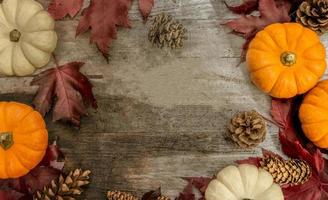 feestelijk herfstdecor van pompoenen, dennen en bladeren op een houten ondergrond. concept van thanksgiving day of halloween. plat lag herfstcompositie met kopieerruimte. foto