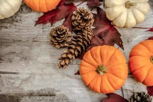 feestelijk herfstdecor van pompoenen, dennen en bladeren op een houten ondergrond. concept van thanksgiving day of halloween. plat lag herfstcompositie met kopieerruimte. foto