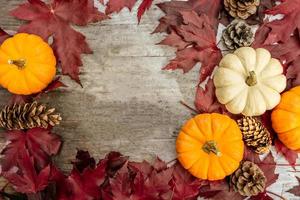 feestelijk herfstdecor van pompoenen, dennen en bladeren op een houten ondergrond. concept van thanksgiving day of halloween. plat lag herfstcompositie met kopieerruimte. foto