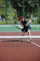 jonge vrouw speelt tennisspel buiten foto