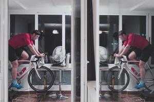 Mens wielersport Aan de machine trainer hij is oefenen in de huis Bij nacht spelen online fiets racing spel foto