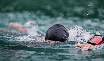 triatlonatleet die op meer zwemt die wetsuit draagt foto