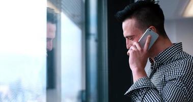 bedrijf Mens pratend Aan cel telefoon, op zoek uit kantoor venster foto