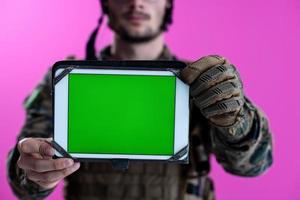 soldaat tonen een tablet met een blanco groen scherm foto