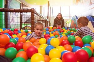 jong mam spelen met kinderen in zwembad met kleurrijk ballen foto