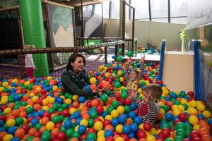 jong mam met haar kinderen in een kinderen speelkamer foto