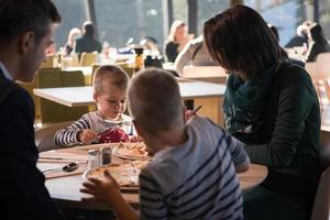 jong ouders genieten van lunch tijd met hun kinderen foto