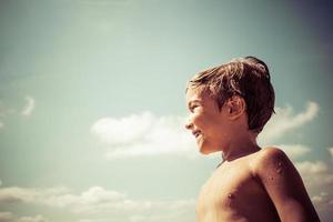 gelukkig jongen tegen de lucht gedurende zomer dag. foto