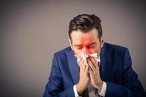 ziek zakenman blazen neus- in een zakdoek. foto