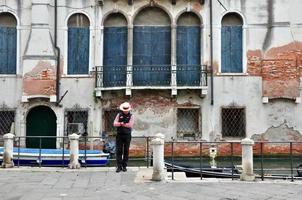 Venetiaanse gondelier kom tot rust uit van gondel met de oude steen muur Aan achtergrond foto