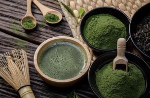 Japans biologisch matcha groen thee poeder in kom met draad vliegenmepper en groen thee blad Aan houten achtergrond, biologisch Product van de natuur voor gezond met traditioneel stijl foto