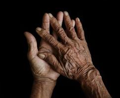 de oud handen grootmoeder in een zwart achtergrond foto