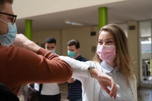 studenten groet nieuw normaal coronavirus handdruk en elleboog stoten foto