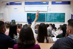 vrouw leerling zittend in de klasse en verhogen hand- omhoog foto