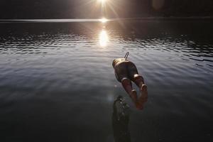 triatlon atleet jumping in naar water en beginnend met opleiding foto