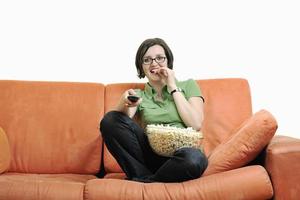 jong vrouw eten popcorn Aan oranje sofa foto