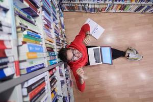 de studenten toepassingen een notitieboekje, laptop en een school- bibliotheek foto