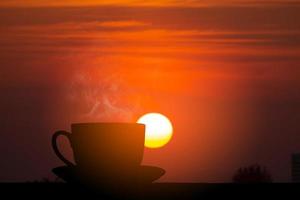 silhouet heet koffie en zonsopkomst foto